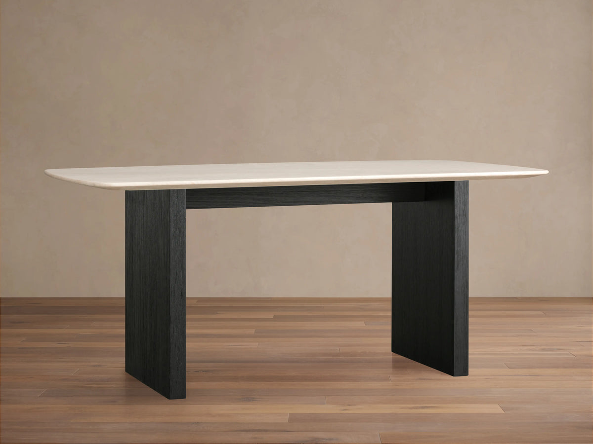 Saint Germain dining table with a cream marble top and solid black wood base, set against a neutral background on a wooden floor.