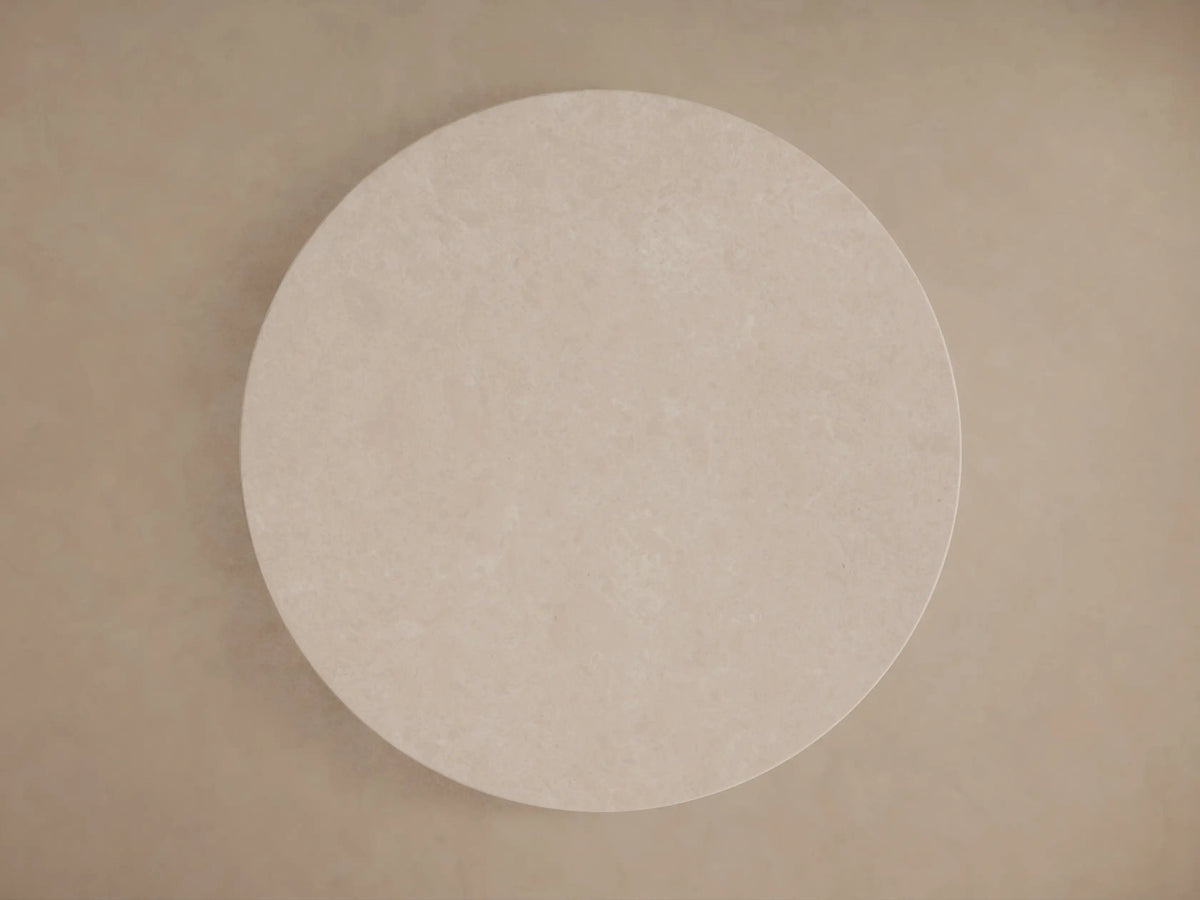 Round table with a cream marble top viewed from above, showing subtle natural variations and patterns on a neutral background.