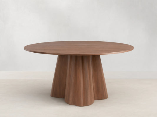 Round wooden dining table with a smooth top and a unique, flared pedestal base. Light brown finish on wood grain.