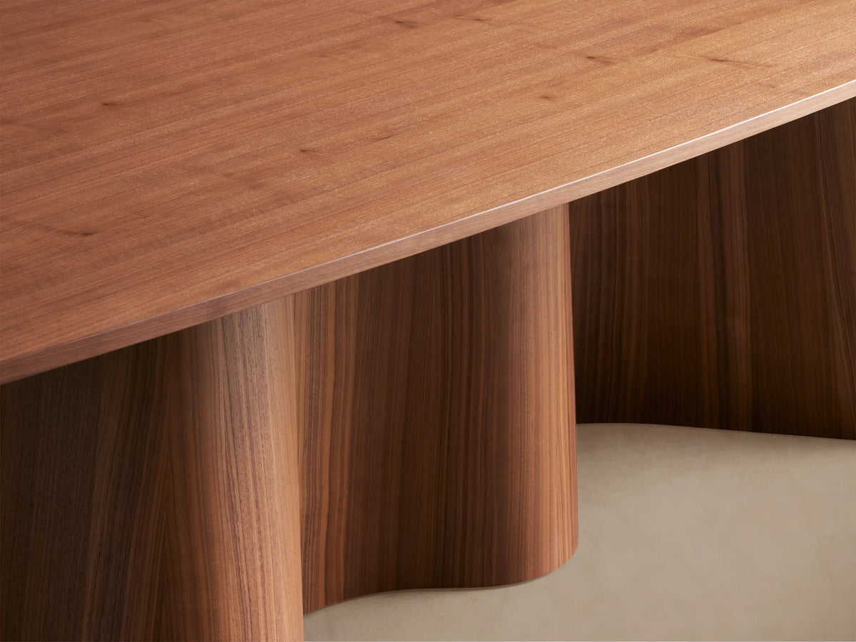 Cortina Dining Table: elegant walnut wood with a sleek, subtly rounded top and a distinctive wavy pedestal base.