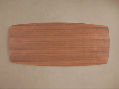 Close-up of Cortina Dining Table, showcasing its smooth American walnut wood surface and elegant, wavy, curved base.