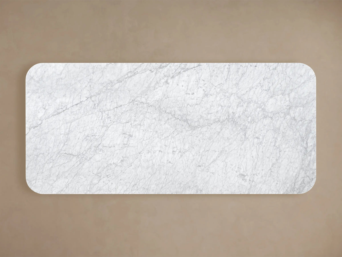 Top view of the white honed Carrara marble top of the Coventry Dining Table, showing its rectangular shape with rounded corners.