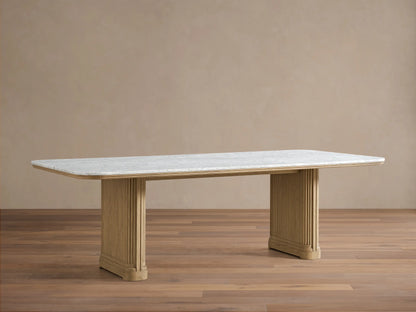 Front view of the Coventry Dining Table, featuring a white Carrara marble top and two light oak reeded pedestal bases.