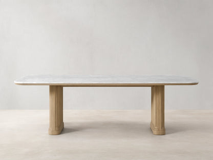 Front view of the Coventry Dining Table with a white Carrara marble top, supported by two oak wood bases with reeded detailing.