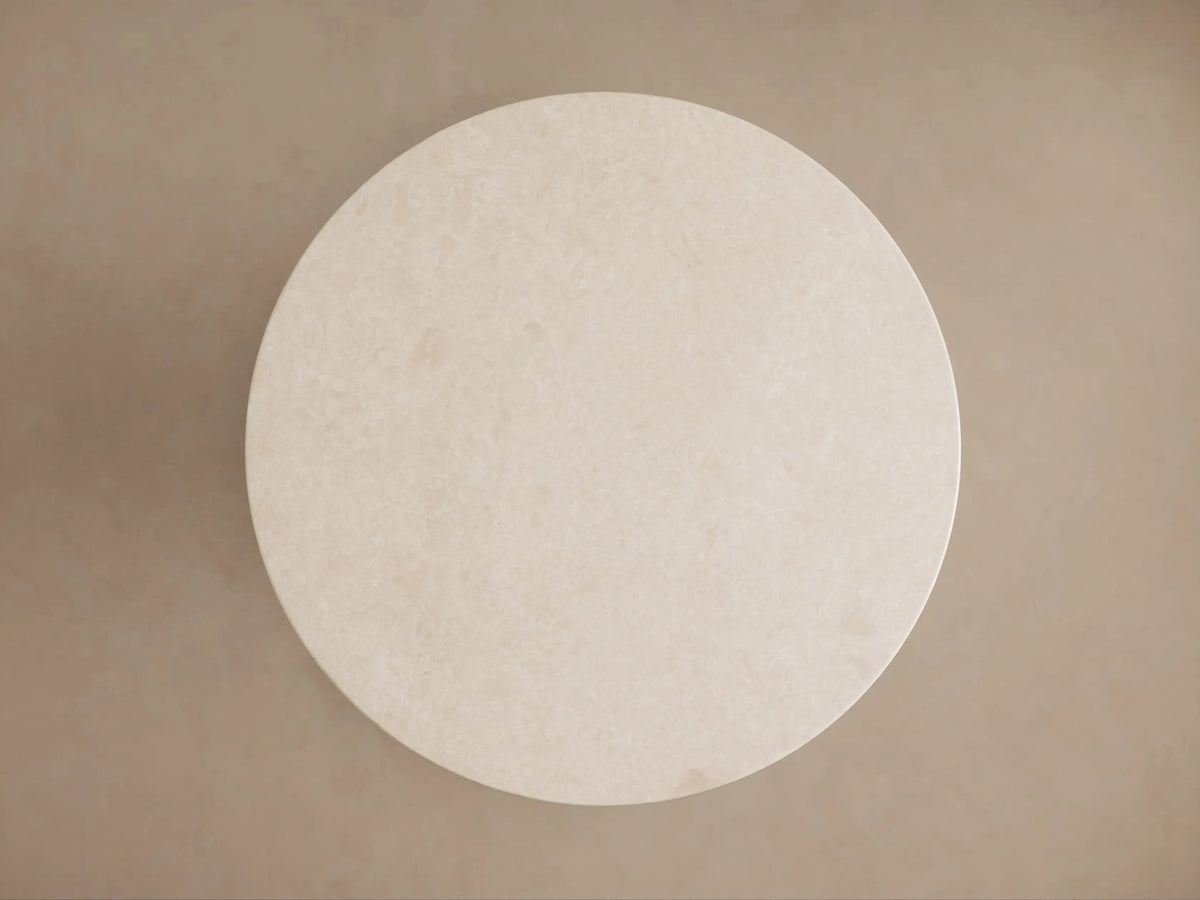 Danae Bistro Table: Angled view of its round, creamy beige marble top with subtle natural veining and part of the fluted base.