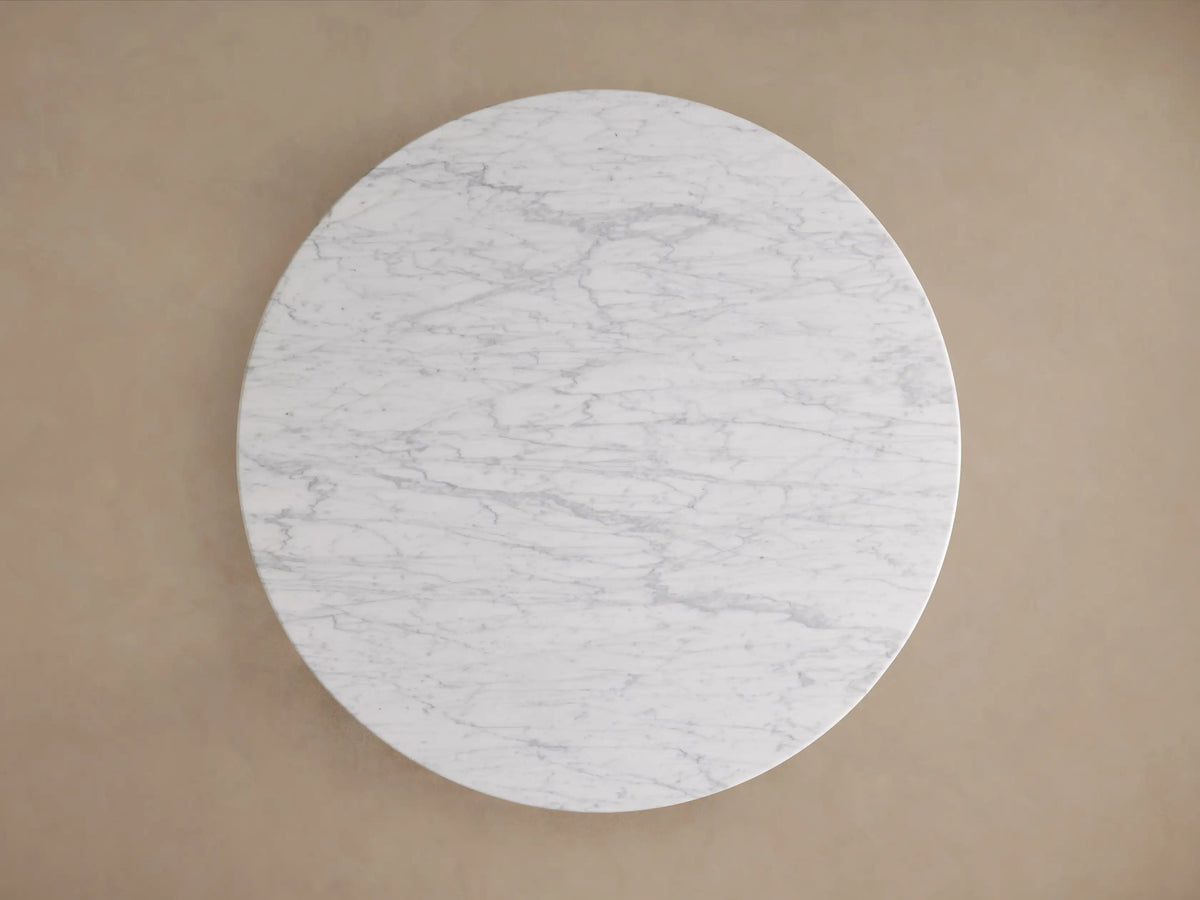 Danae Round Stone Dining Table featuring a smooth, white marble surface with natural gray veining and a fluted base design.