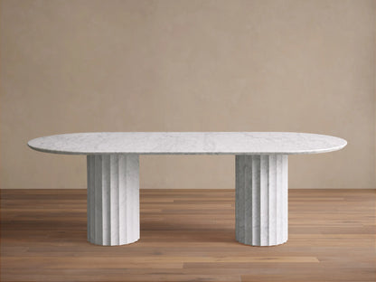 Danae Stone Dining Table: White oval marble top with subtle grey veining, resting on two fluted marble bases on a wood floor.