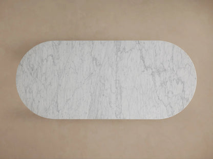 Close-up of Danae Stone Dining Table: white marble top with grey veins, resting on fluted marble columns. Beige background.