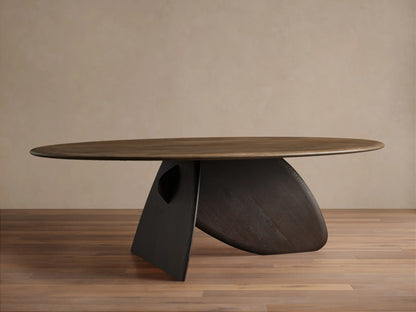 Pebble Dining Table with an oval russet oak top and a dark espresso sculptural, pebble-shaped base with a metal leg.
