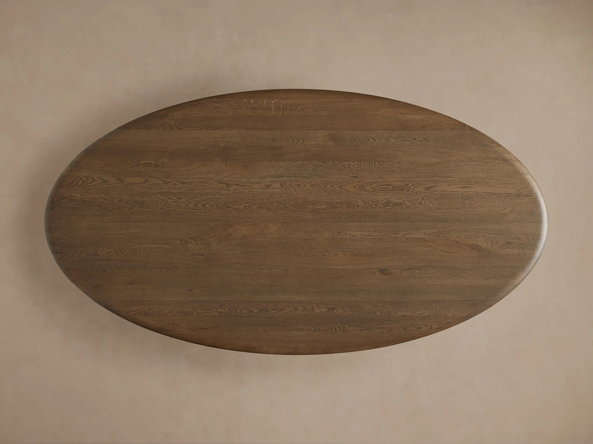 Pebble Dining Table close-up: smooth Russet oak top connects to a dark Espresso curved, sculptural base.