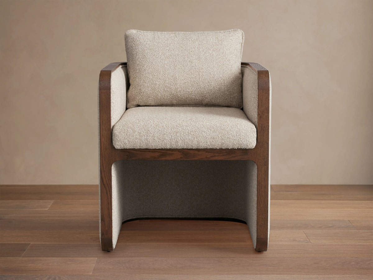 Dempsey Dining Chair in Mocha with oak wood frame, cushioned seat and backrest in light beige fabric; set on hardwood floor.
