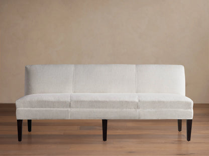 Light-colored Eaton Settee with textured Crypton fabric, channel-stitching, and dark tapered legs, front view against a light wall.
