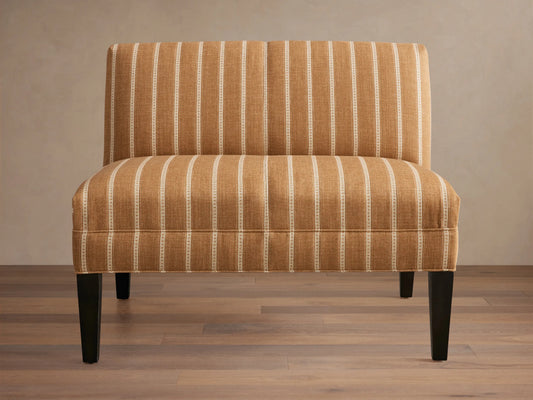 Eaton Bench upholstered in warm brown fabric with light vertical stripes, on four dark, tapered wooden legs. Front view.