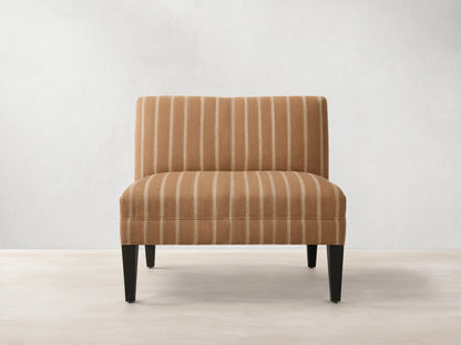 Eaton Bench upholstered in warm brown fabric with light vertical stripes, on four dark, tapered wooden legs. Front view.