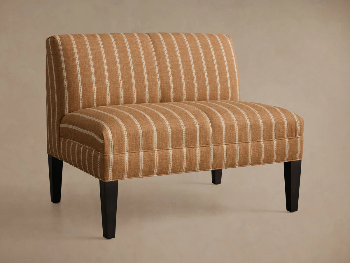 Eaton Bench upholstered in warm brown fabric with light vertical stripes, on four dark, tapered wooden legs. Front view.