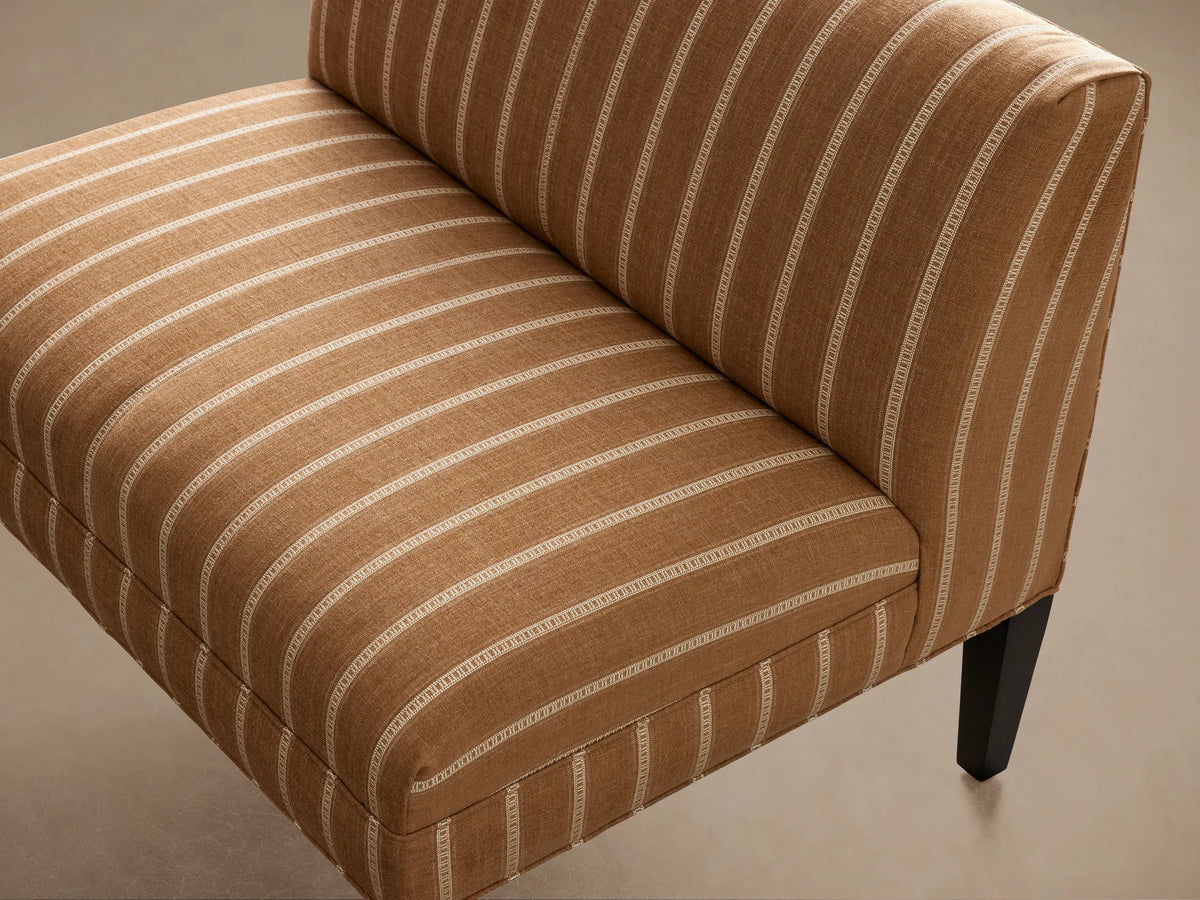 Eaton Bench, upholstered in brown fabric with vertical white stripes, dark wooden legs, angled front view.