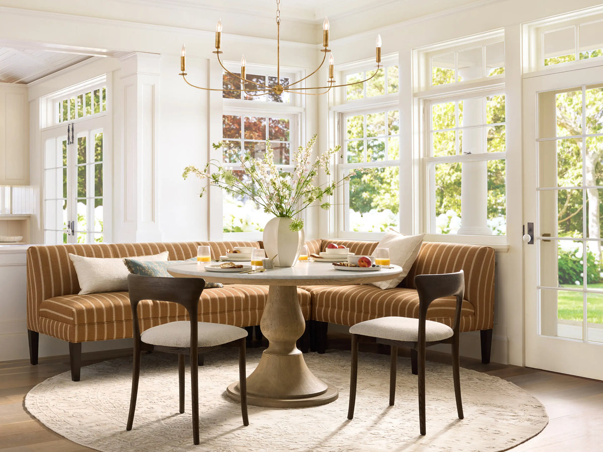 Eaton Banquette, L-shaped, upholstered in brown fabric with vertical white stripes, dark tapered legs, on wood floor.