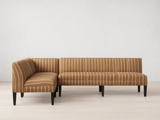 Eaton Banquette, L-shaped, upholstered in brown fabric with vertical white stripes, dark tapered legs, on wood floor.