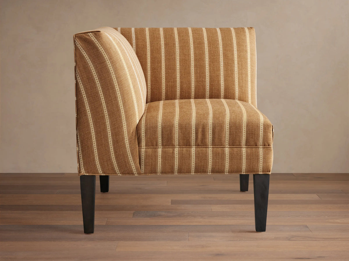 Eaton Corner chair upholstered in brown fabric with thin white vertical stripes, on dark wooden legs, angled.