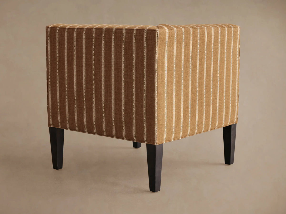 Eaton Corner chair upholstered in brown fabric with white pinstripes, showing a curved armrest, seat, and a dark leg.