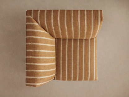 Eaton Corner chair upholstered in golden-tan fabric with white vertical pinstripes, standing on dark tapered legs, angled view.