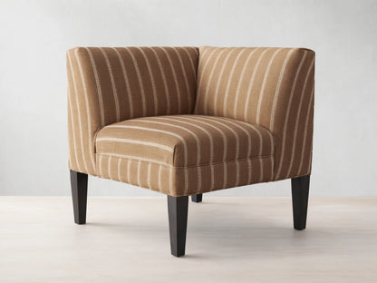 Eaton Corner chair upholstered in brown fabric with thin white vertical stripes, on dark wooden legs, angled.