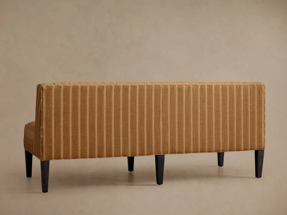 Angled close-up of Eaton Settee, warm brown fabric with cream pinstripes, dark wood leg on left.