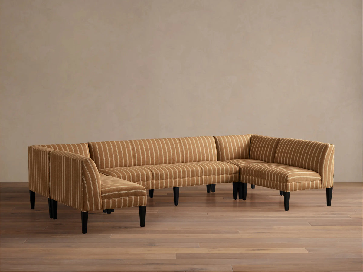 Eaton U-Shaped Banquette in light brown & white striped fabric, U-shaped, with dark tapered legs on a wood floor.