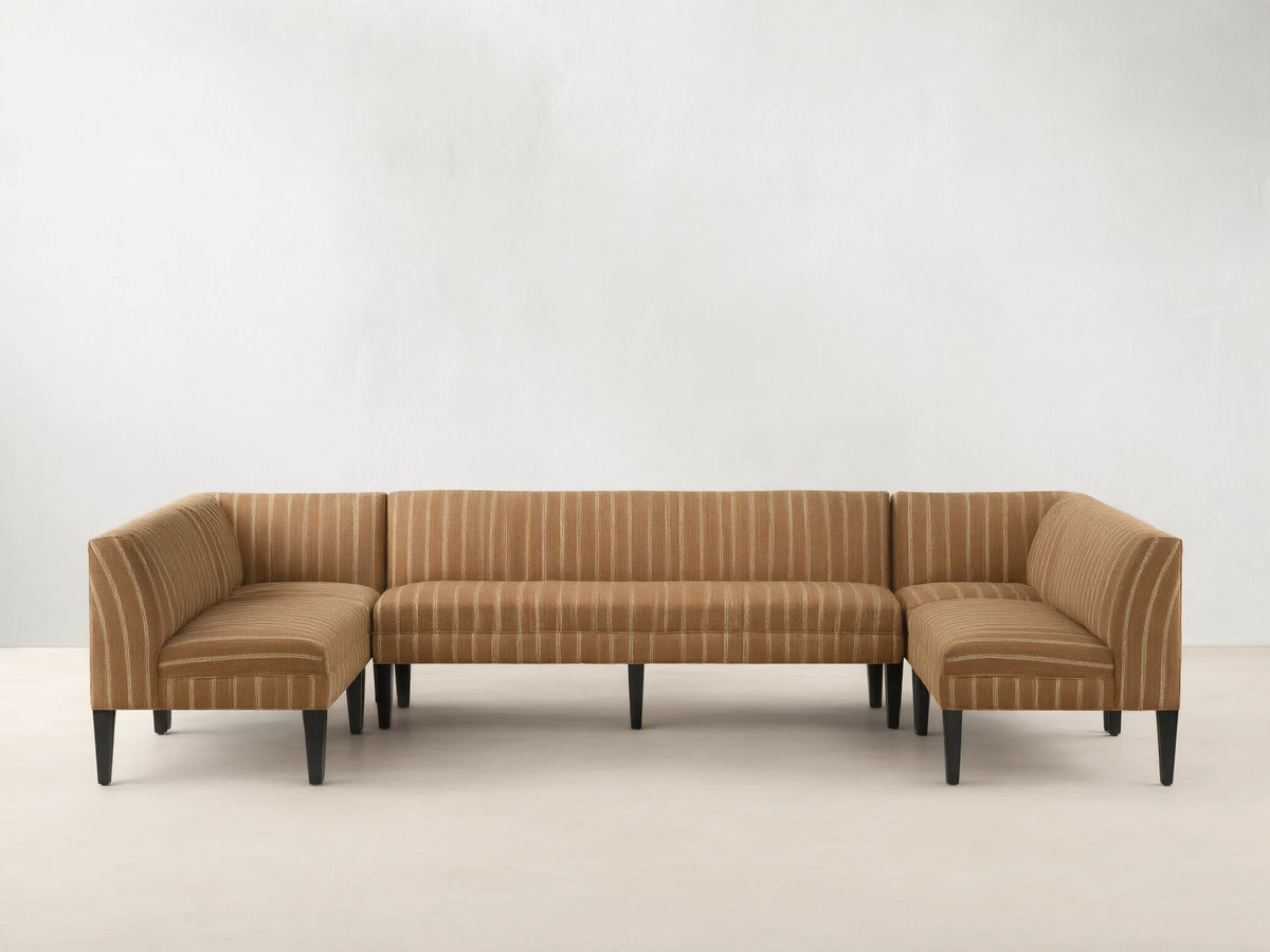 Eaton U-Shaped Banquette in light brown & white striped fabric, U-shaped, with dark tapered legs on a wood floor.
