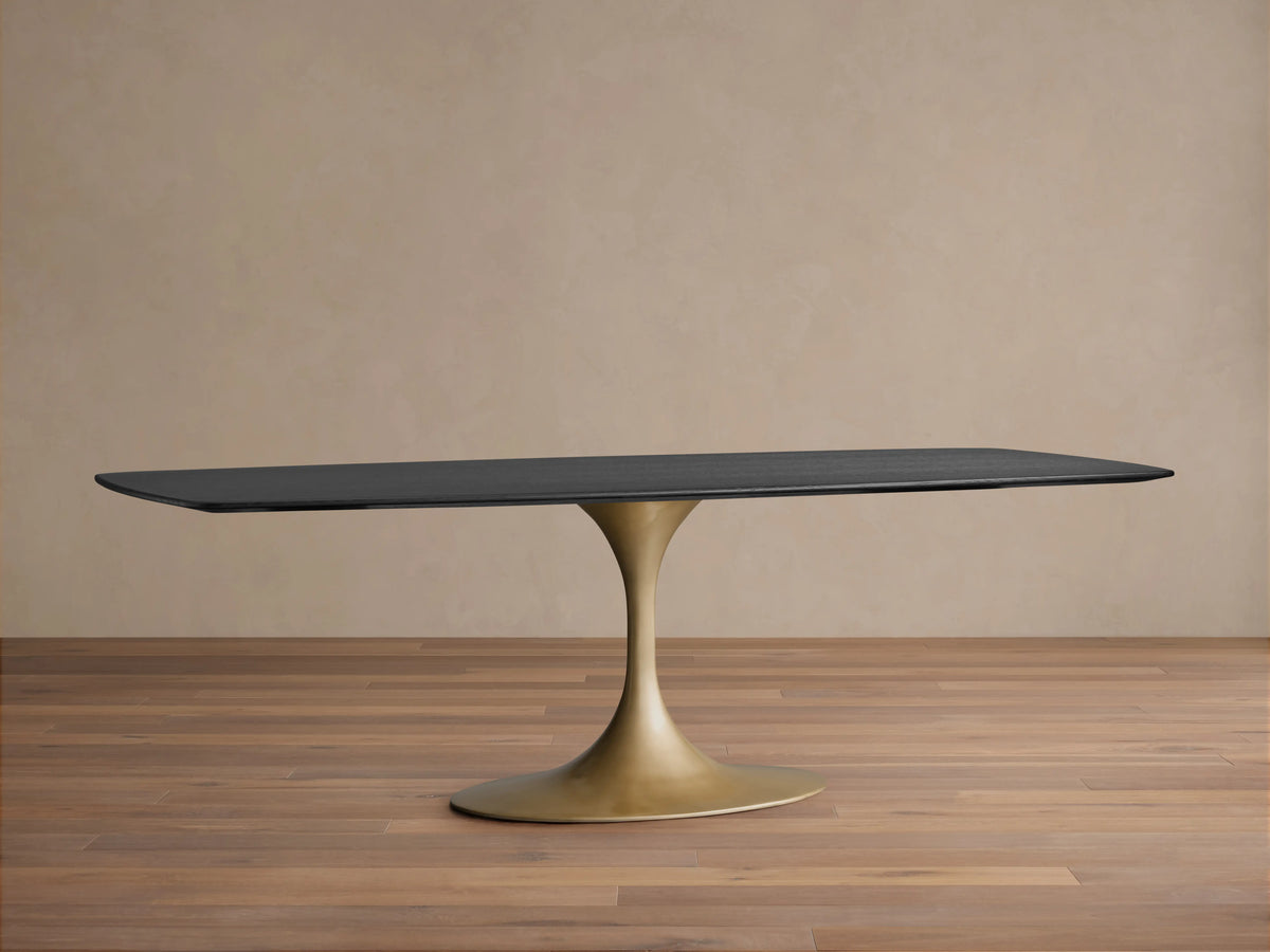 Saint Germain Wood Dining Table with ebony finish, rectangular top, and sleek gold steel base, on wood floor background.