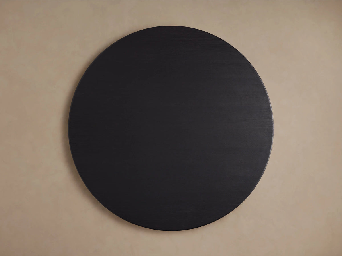 Round wooden dining table with an ebony-finished oak tabletop, displaying a smooth, dark grain texture against a neutral background.