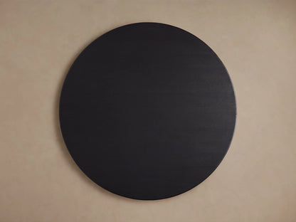 Round wooden dining table with an ebony-finished oak tabletop, displaying a smooth, dark grain texture against a neutral background.
