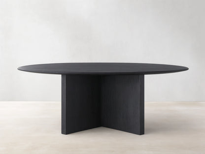 Saint Germain round dining table with an ebony wood top and a sturdy wood base, set on a light wood floor.