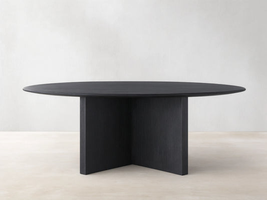 Saint Germain round dining table with an ebony wood top and a sturdy wood base, set on a light wood floor.