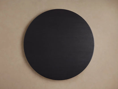 Round wooden dining table in ebony finish, showing a close-up of the solid oak top with visible wood grain texture on a neutral background.