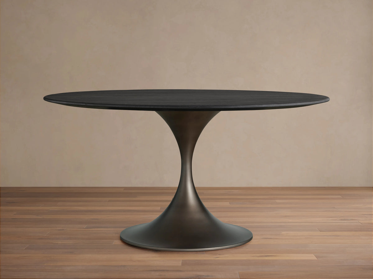 Saint Germain Round Wood Dining Table with ebony-finished oak top and steel Launette base on a wooden floor.