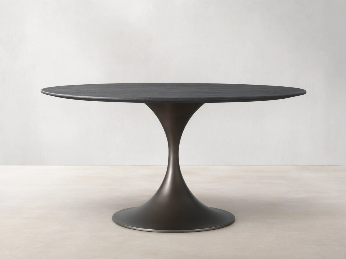 Saint Germain Round Wood Dining Table with ebony-finished oak top and steel Launette base on a wooden floor.