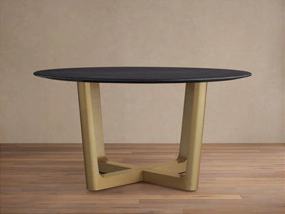 The Saint Germain Round Wood Dining Table features a dark oak tabletop and a wide, V-shaped Rennes base in antique brass on a wood floor.