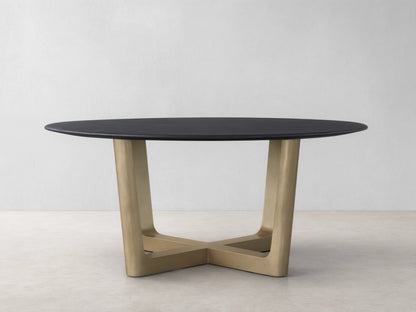 The Saint Germain Round Wood Dining Table features a dark oak tabletop and a wide, V-shaped Rennes base in antique brass on a wood floor.