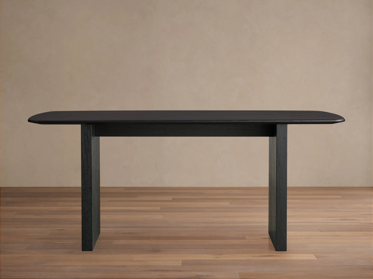 Saint Germain dining table with solid oak top and rectangular base, finished in dark Ebony, on wooden floor.