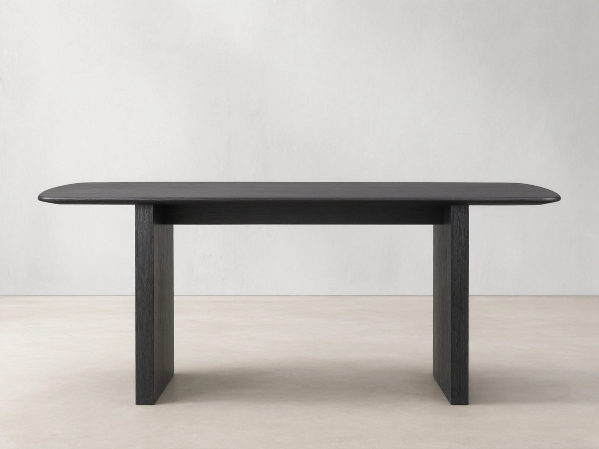 Saint Germain dining table with solid oak top and rectangular base, finished in dark Ebony, on wooden floor.