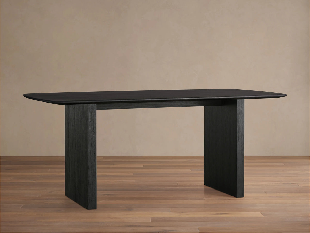 Saint Germain dining table with solid oak top and rectangular base, finished in dark Ebony, on wooden floor.
