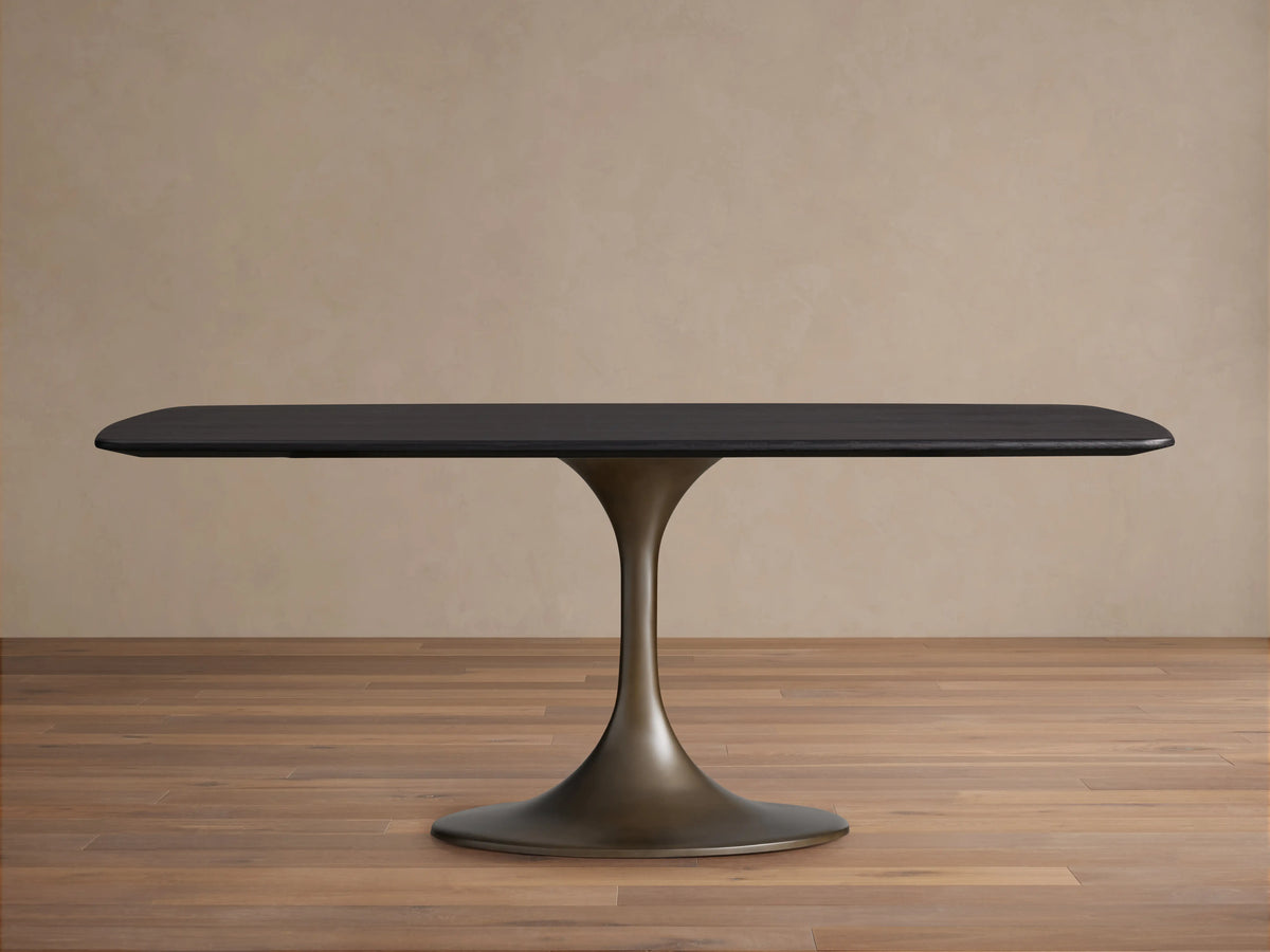Saint Germain Wood Dining Table with a sleek rectangular top in Ebony finish and a sculpted steel Launette base on wooden flooring.