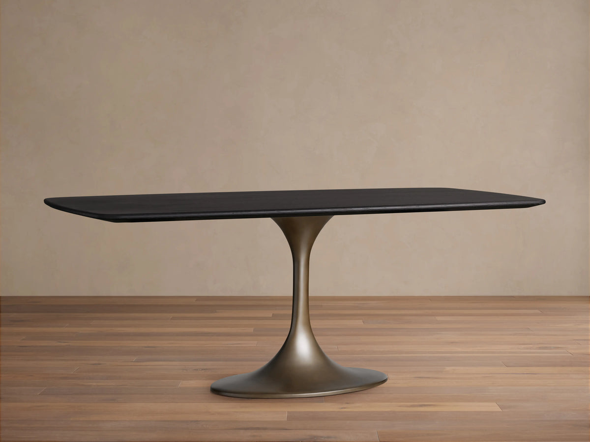 Saint Germain Wood Dining Table with a sleek rectangular top in Ebony finish and a sculpted steel Launette base on wooden flooring.
