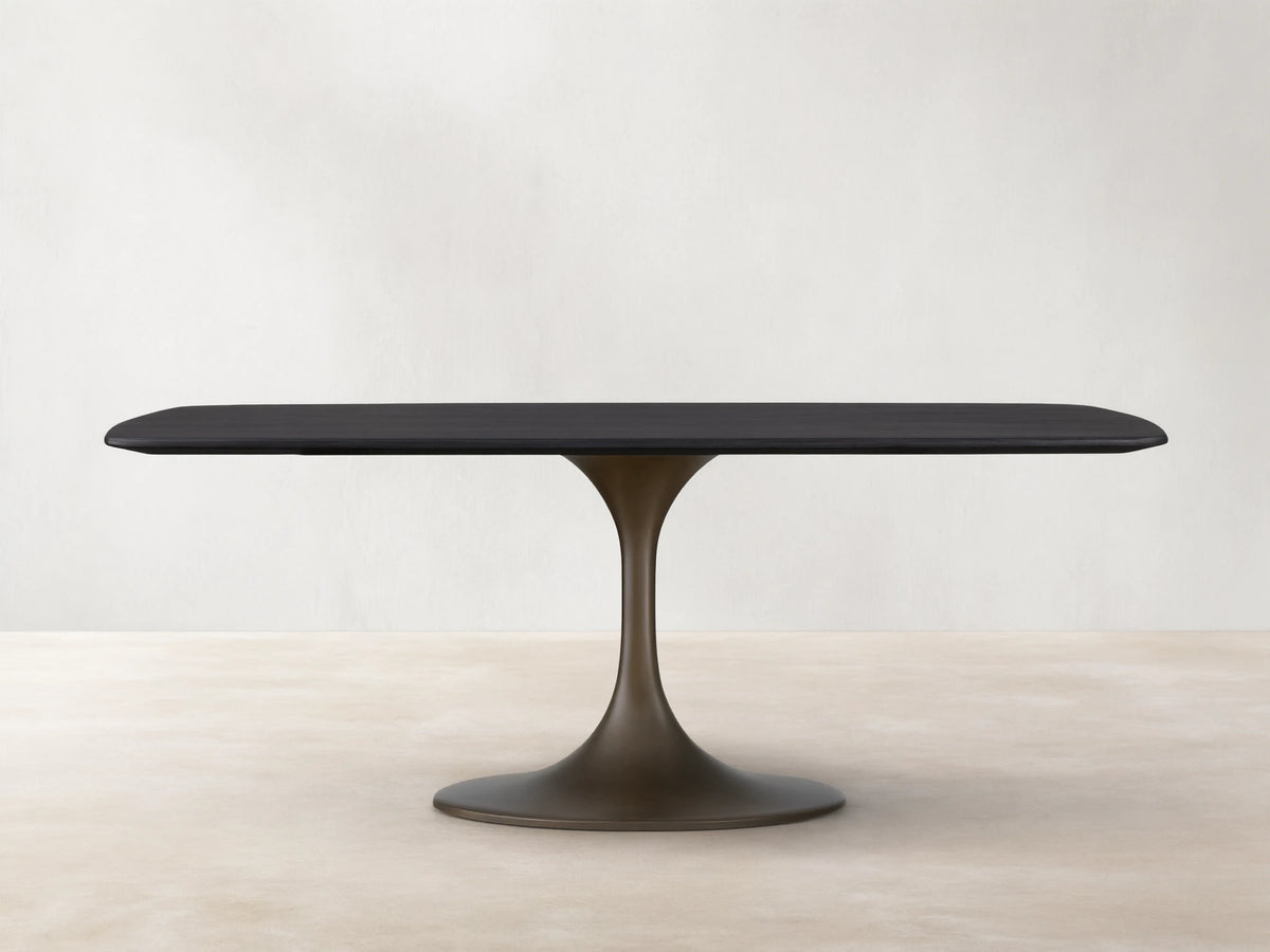Saint Germain Wood Dining Table with a sleek rectangular top in Ebony finish and a sculpted steel Launette base on wooden flooring.