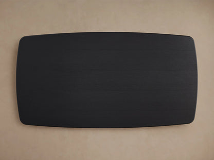 Saint Germain Wood Dining Table with Ebony finish, showing a smooth, dark oak tabletop with visible wood grain, rounded corner, light background.