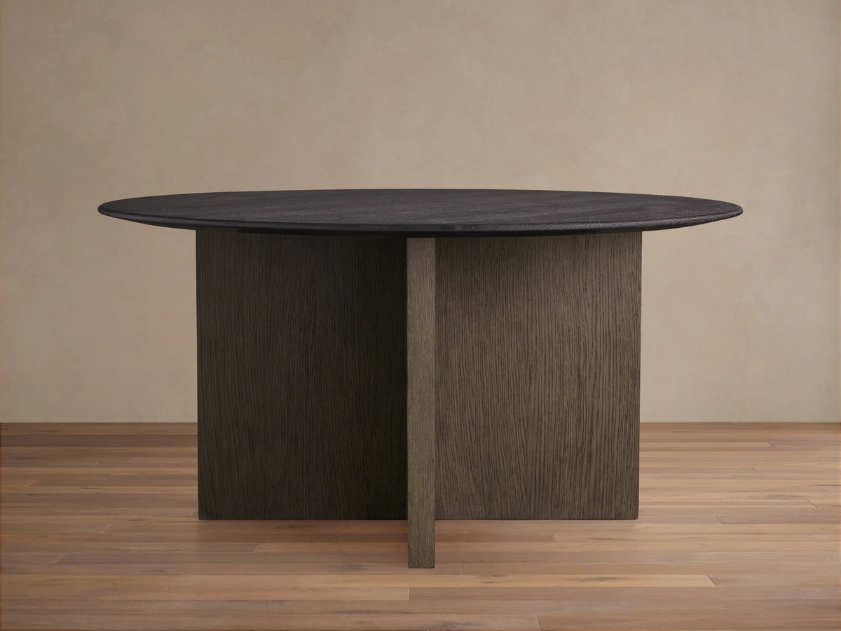 Saint Germain Round Wood Top Dining Table with solid dark oak tabletop and V-shaped wood base in contrasting shade on wooden floor.