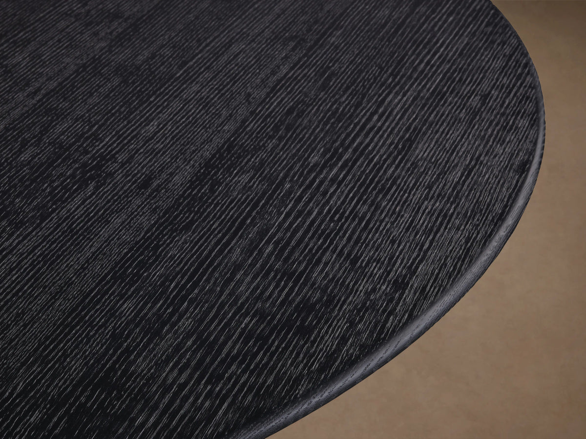 Saint Germain round dining table with dark wood tabletop and U-shaped wooden Rennes base on a wooden floor.