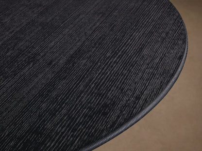 Saint Germain round dining table with dark wood tabletop and U-shaped wooden Rennes base on a wooden floor.