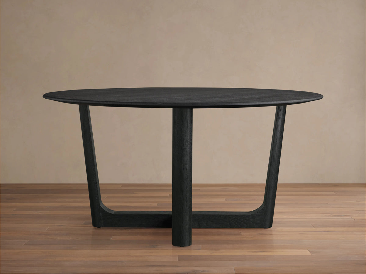 Saint Germain Round Wood Dining Table with ebony-finished oak tabletop and intertwined Rennes base in a bright, neutral room.